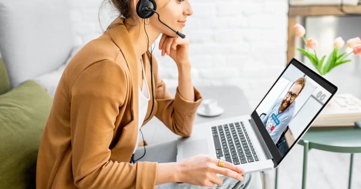 Female assistant working from home with headphones as as she meets with a colleague virtually
